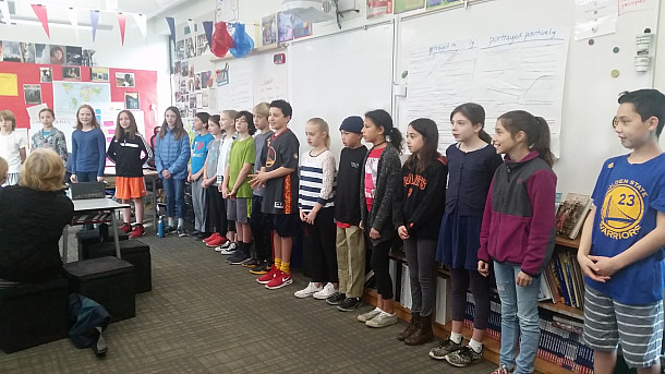 Students open the community share reciting the poem Home by Warson Shire.